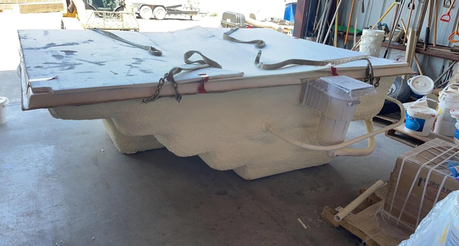 Upturned spa shell coated in closed-cell spray foam in the shop